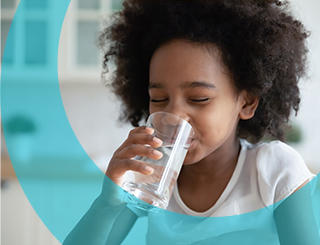 Petite fille qui boit un verre d'eau