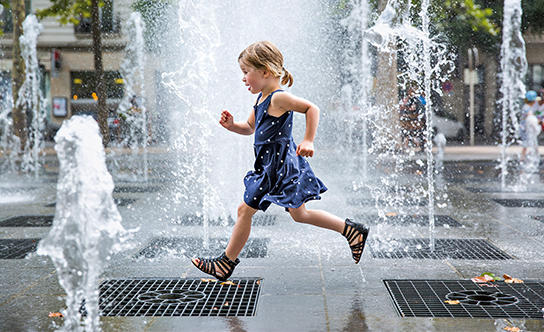 Enfant courant entre des jets d'eau